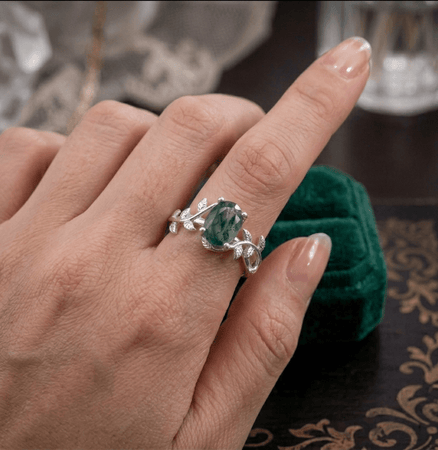 Anello indossato con gemma di agata muschiata che mostra i filamenti interni simili a muschio su montatura in argento.