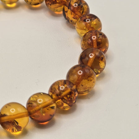 Dettaglio perle di Ambra Russa lucida su bracciale elastico