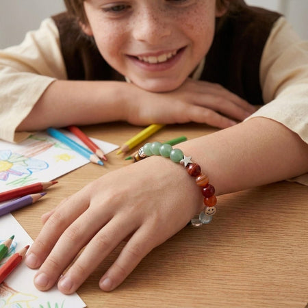Bracciale elastico con pietre naturali indossato comodamente sul polso di un bambino sorridente.