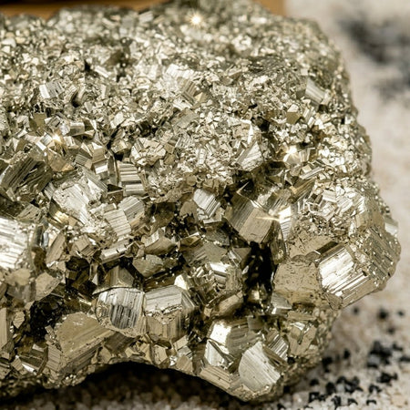Primo piano di Pirite grezza naturale con cristalli cubici lucenti e riflessi metallici dorati.
